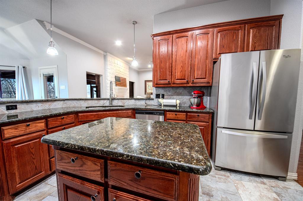 9001 Ravenswood Road Granbury, TX 76049 - Photo 13 of 38 Kitchen featuring stainless steel appliances, dark stone counters, hanging light fixtures, a kitchen island, and decorative backsplash