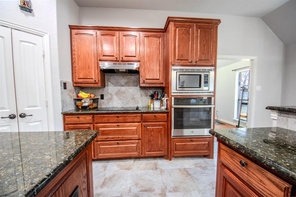 9001 Ravenswood Road Granbury, TX 76049 - Photo 14 of 38 Kitchen with stainless steel appliances, wood finish cabinets, and dark stone countertops