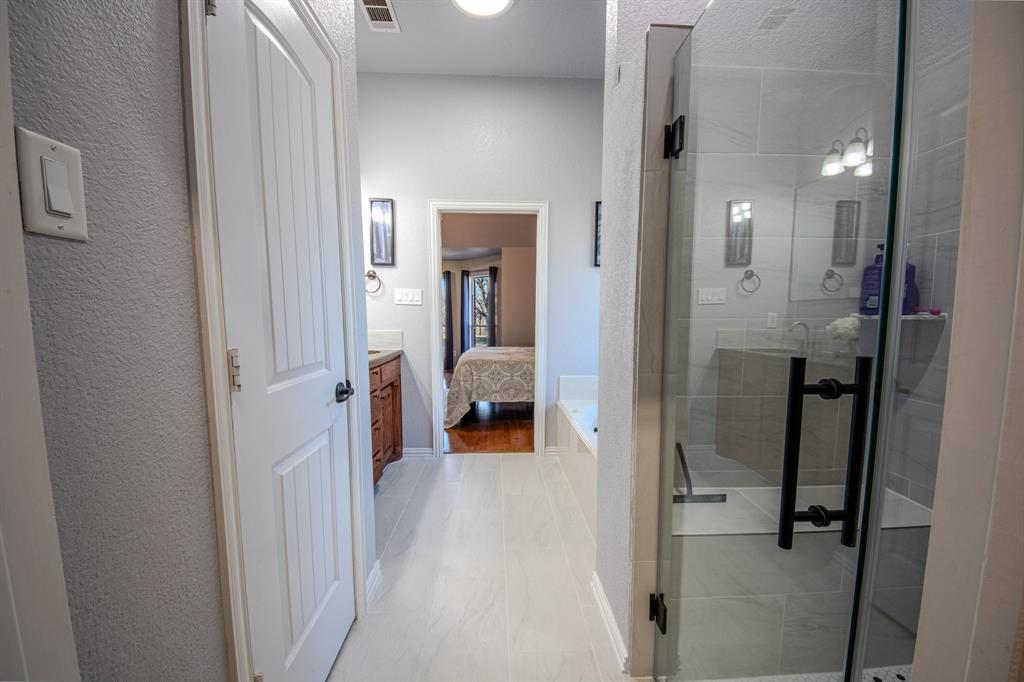 9001 Ravenswood Road Granbury, TX 76049 - Photo 23 of 38 Ensuite bathroom with a stall shower, vanity, and a textured wall