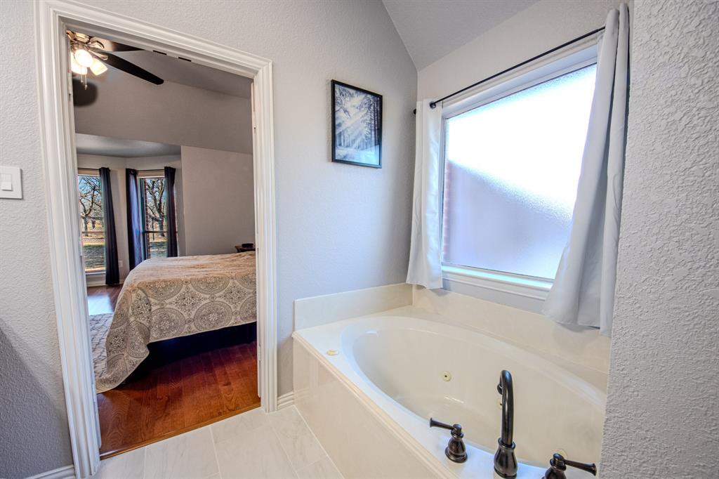 9001 Ravenswood Road Granbury, TX 76049 - Photo 25 of 38 Full bathroom with a textured wall, ensuite bath, a whirlpool tub, lofted ceiling, and a ceiling fan