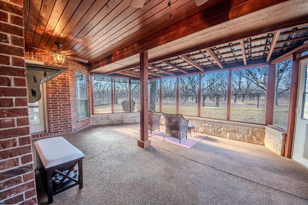 9001 Ravenswood Road Granbury, TX 76049 - Photo 30 of 38 Unfurnished sunroom with a patio area, a ceiling fan, carpet floors, wood ceiling, and brick wall