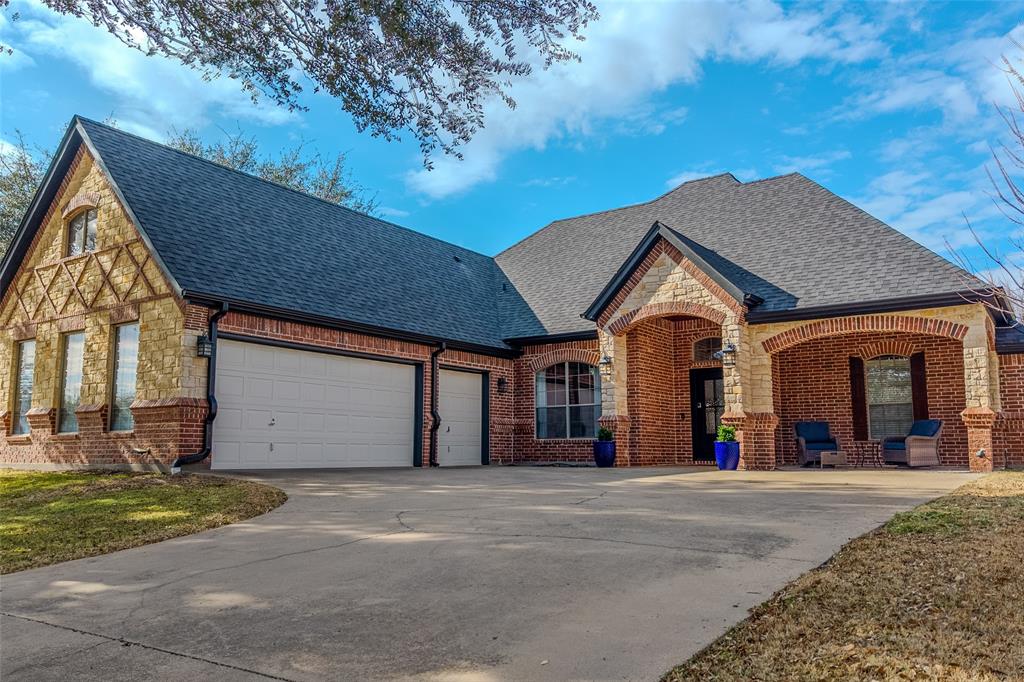 9001 Ravenswood Road Granbury, TX 76049 - Photo 3 of 38 View of front of home with stone siding, a shingled roof, driveway, an attached garage, and brick siding