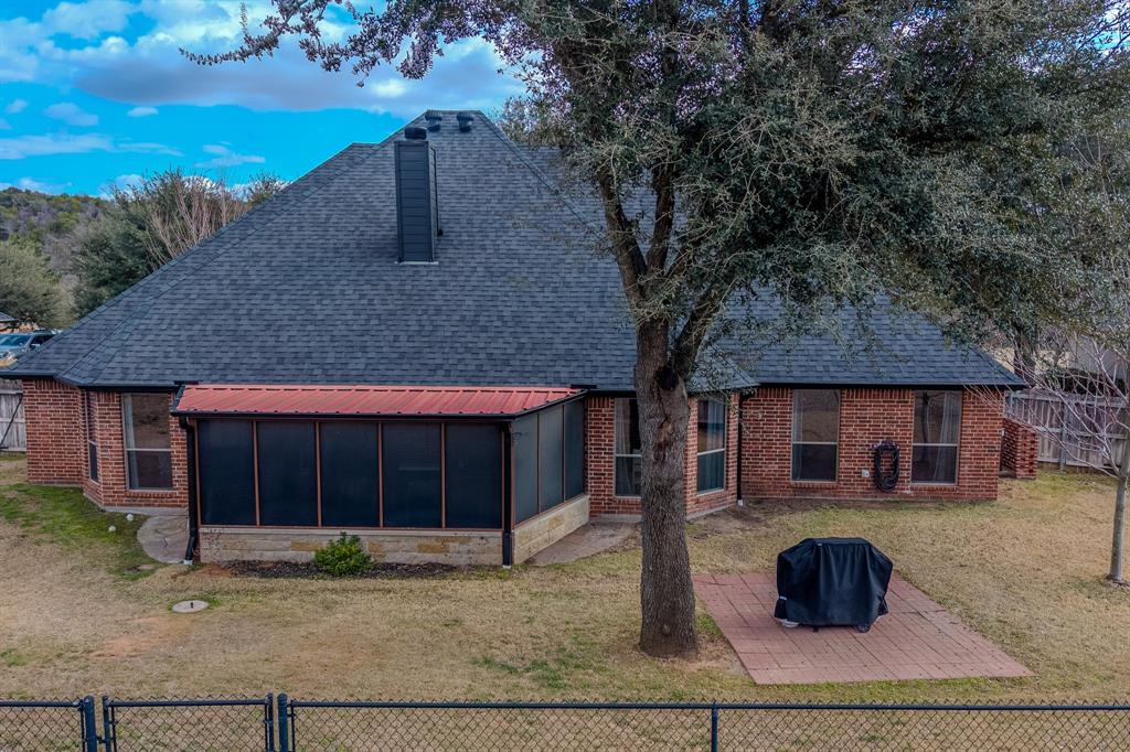 9001 Ravenswood Road Granbury, TX 76049 - Photo 35 of 38 Back of property with a fenced backyard, a gate, a shingled roof, a patio area, and a sunroom