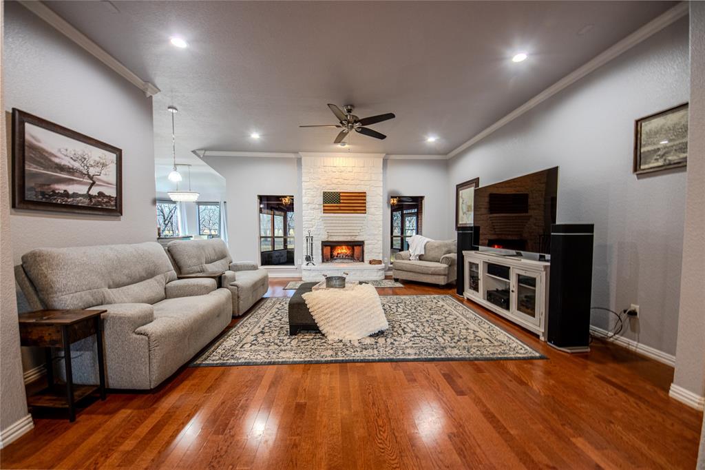 9001 Ravenswood Road Granbury, TX 76049 - Photo 6 of 38 Living area with hardwood / wood-style floors, ceiling fan, crown molding, and a fireplace