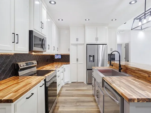 a kitchen that has a lot of cabinets in it with stainless steel appliances granite countertop a stove and a refrigerator