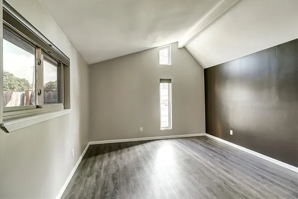 an empty room with wooden floor and windows