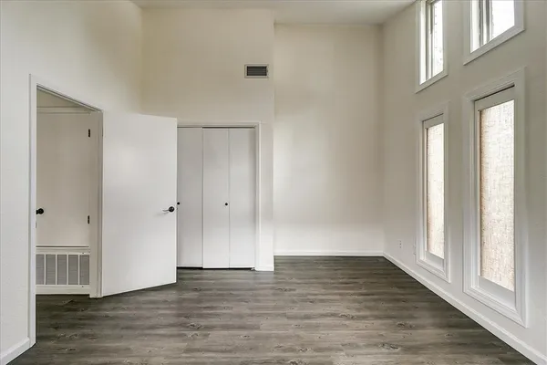 a view of an empty room with wooden floor and a window