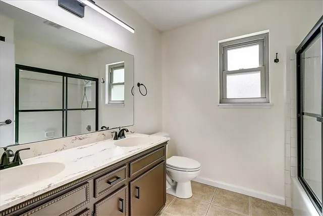 a bathroom with a granite countertop sink toilet and mirror
