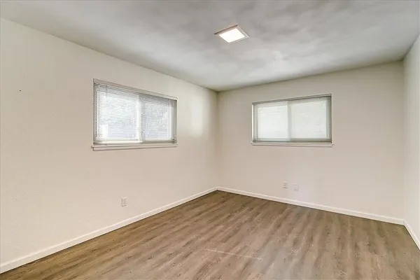 an empty room with wooden floor and windows