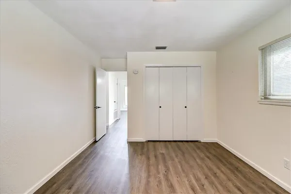 a view of an empty room with wooden floor and a window
