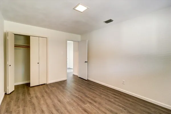 a view of an empty room with wooden floor and closet