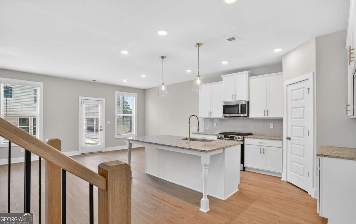 136 Patillo Manor, Unit 9 Stockbridge, GA 30281 - Photo 14 of 18 a kitchen with stainless steel appliances granite countertop a sink a stove and a refrigerator