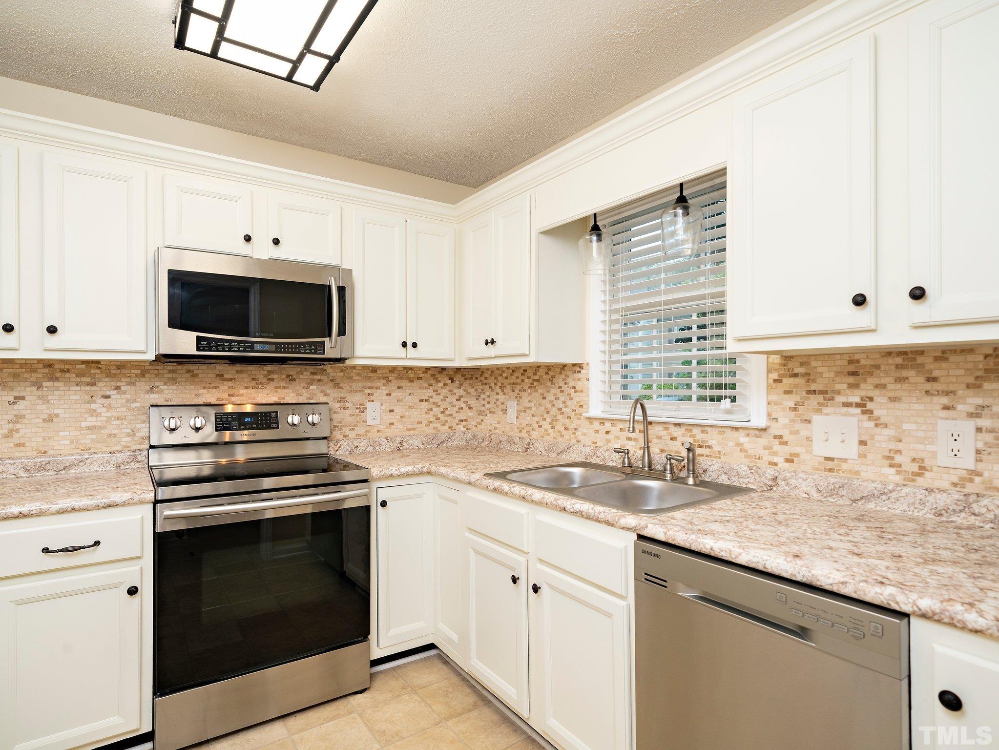 5632 Bridgetowne Way Raleigh, NC 27609 - Photo 4 of 26 a kitchen with granite countertop a stove a sink and a microwave