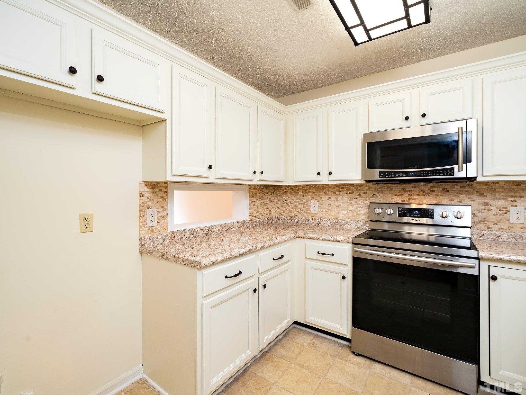 5632 Bridgetowne Way Raleigh, NC 27609 - Photo 5 of 26 a kitchen with granite countertop a stove top oven microwave and cabinets