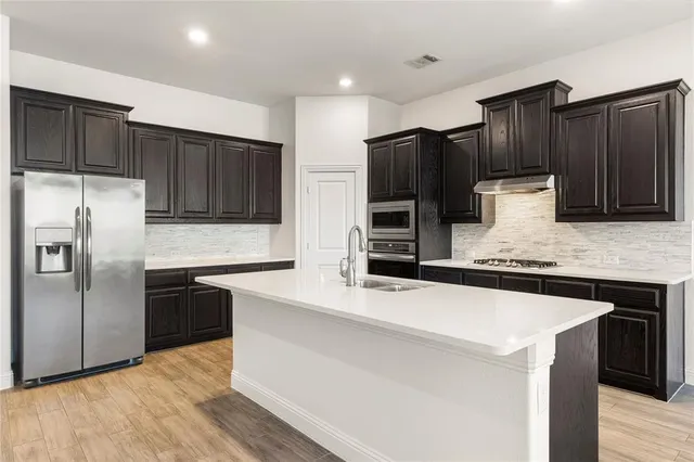a kitchen with stainless steel appliances wooden cabinets a sink and a refrigerator
