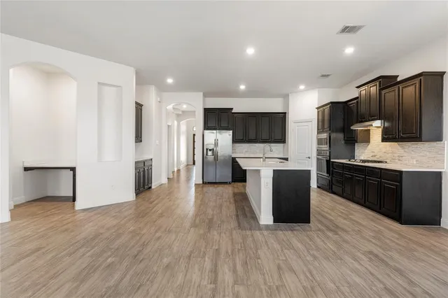 a large kitchen with stainless steel appliances a large counter top a stove and a wooden floors