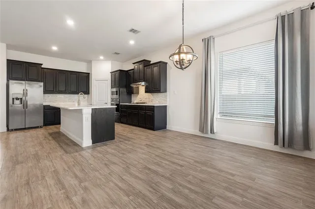 a large kitchen with stainless steel appliances kitchen island granite countertop a large counter top and wooden floors