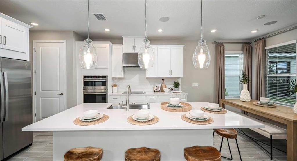 5241 Bowspirit Way St. Cloud, FL 34771 - Photo 5 of 17 a kitchen with stainless steel appliances kitchen island granite countertop a kitchen island and chairs in it
