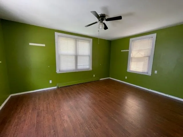 a view of an empty room with wooden floor and a window