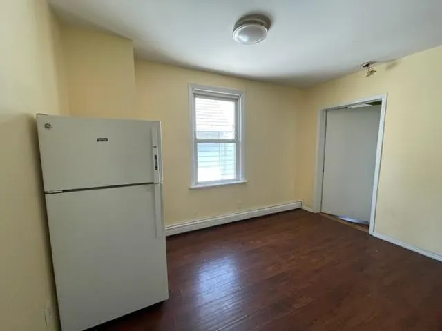 a view of a kitchen with refrigerator and wooden floor
