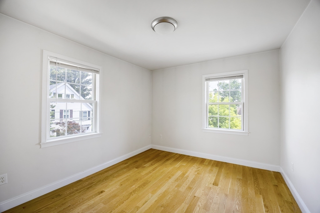 48 Spruce Street, Unit 1 Winchester, MA 01890 - Photo 10 of 29 a view of an empty room with wooden floor and a window
