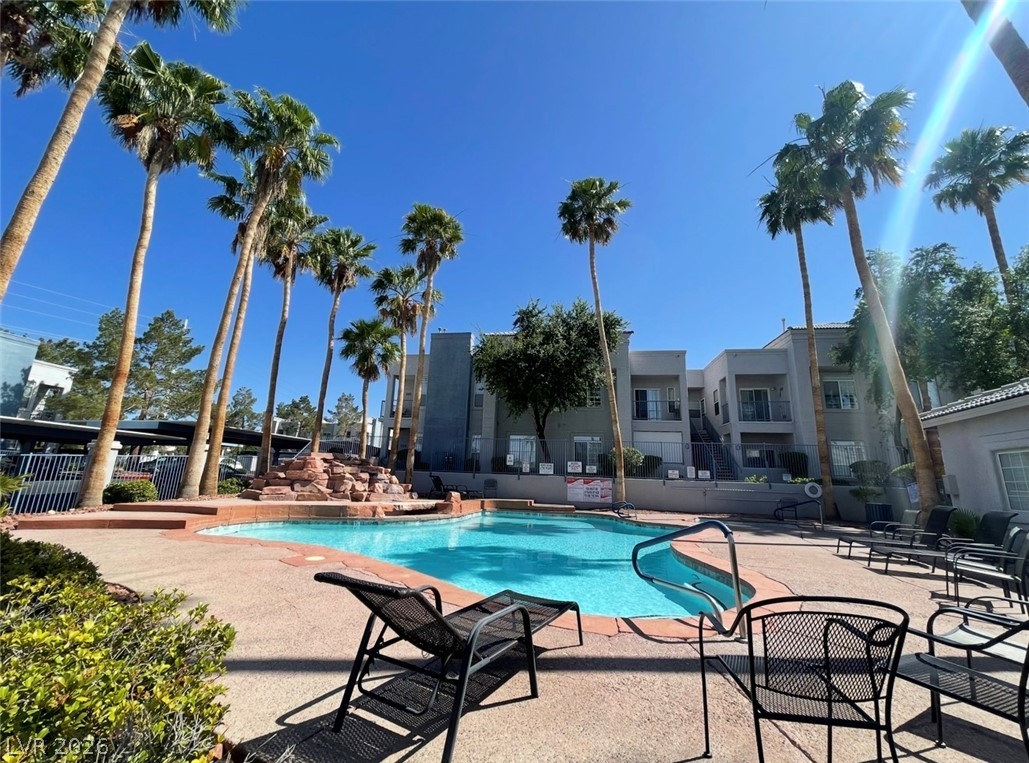 2201 Ramsgate Drive, Unit 915 Henderson, NV 89074 - Photo 8 of 36 Palm trees surround a refreshing pool, creating an inviting oasis within the complex.