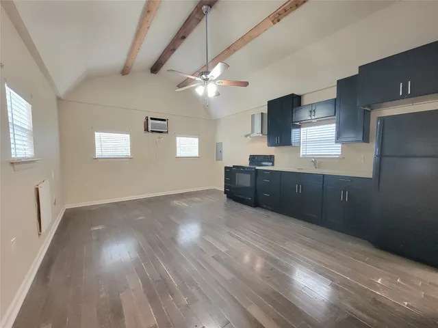 a view of kitchen and empty room with wooden floor