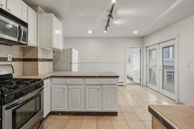 a kitchen with granite countertop white cabinets white stainless steel appliances and a sink