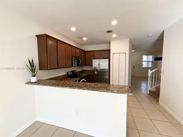 a kitchen with stainless steel appliances granite countertop a refrigerator and a sink