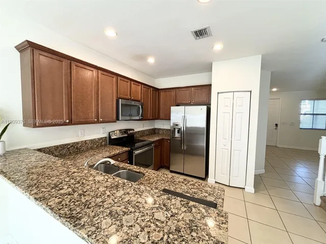 a kitchen with stainless steel appliances granite countertop a refrigerator and a sink