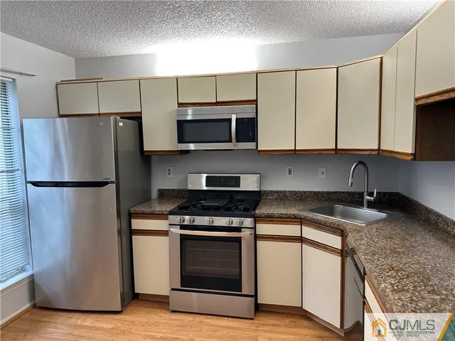 a kitchen with granite countertop a sink stove and refrigerator