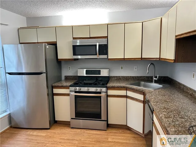 a kitchen with stainless steel appliances granite countertop a refrigerator stove a sink and a microwave