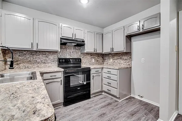 a kitchen with granite countertop wooden cabinets and a stove