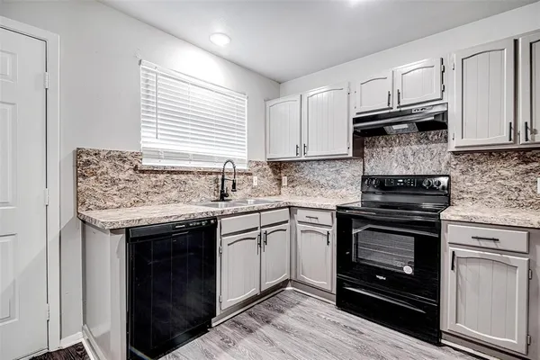 a kitchen with granite countertop a sink stove and cabinets