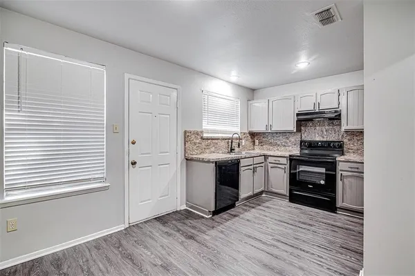 a kitchen with a refrigerator stove and wooden floor