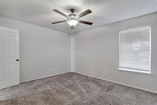 an empty room with a window and a fan