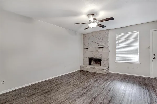 a view of an empty room with wooden floor fireplace and a window