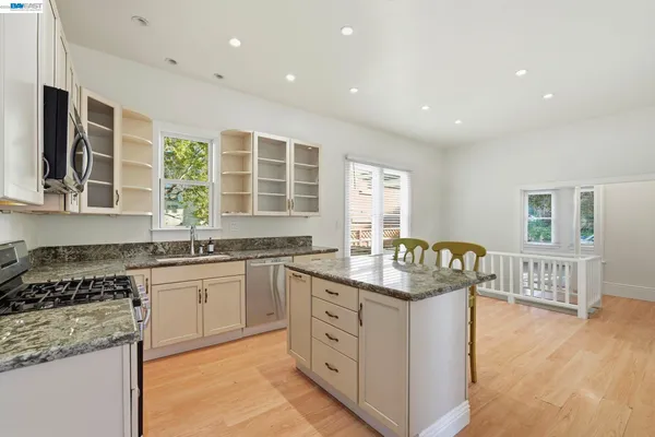 a kitchen with granite countertop kitchen island white cabinets and stainless steel appliances