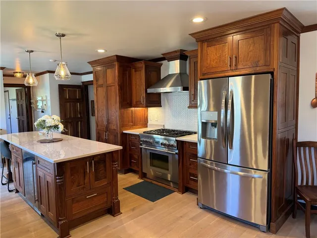 a kitchen with stainless steel appliances granite countertop a refrigerator a stove and a sink