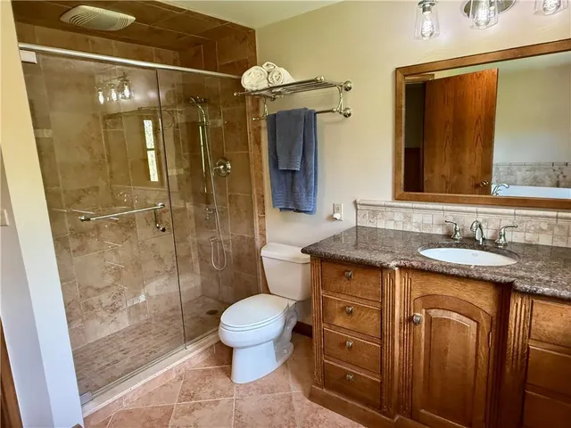 a bathroom with a granite countertop sink toilet and shower
