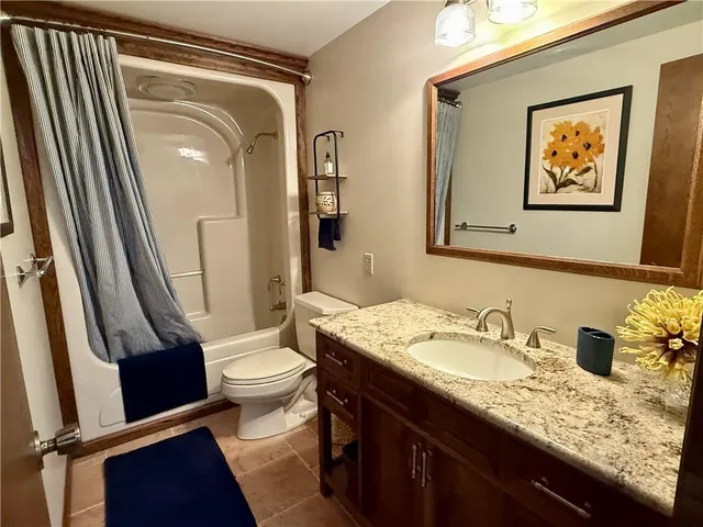 a bathroom with a granite countertop sink toilet and shower