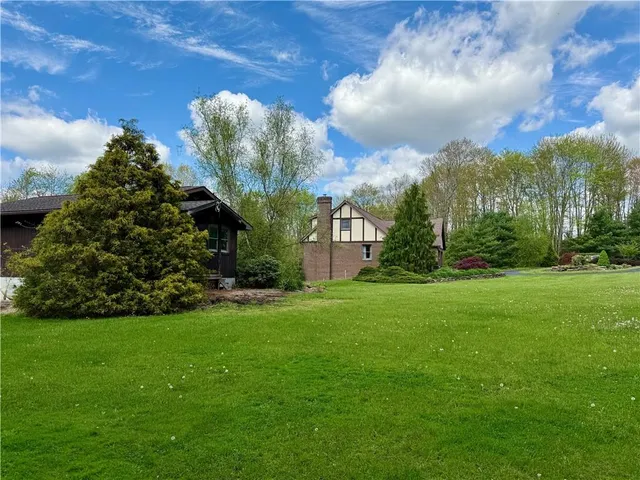 a view of a fountain in front of a brick house with a big yard