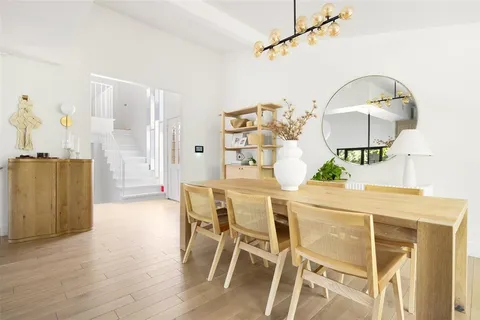 a dining room with wooden floor table and chairs