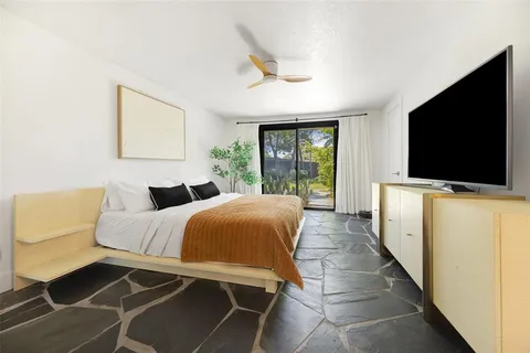 a spacious bedroom with a bed and a flat screen tv