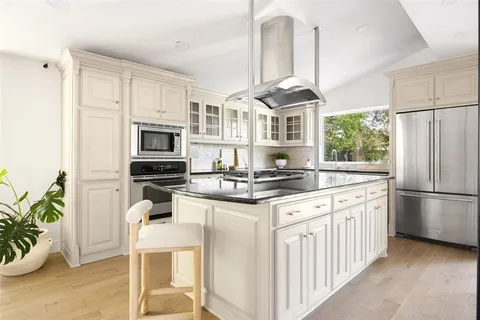 a kitchen with stainless steel appliances granite countertop a stove a refrigerator and a white cabinets