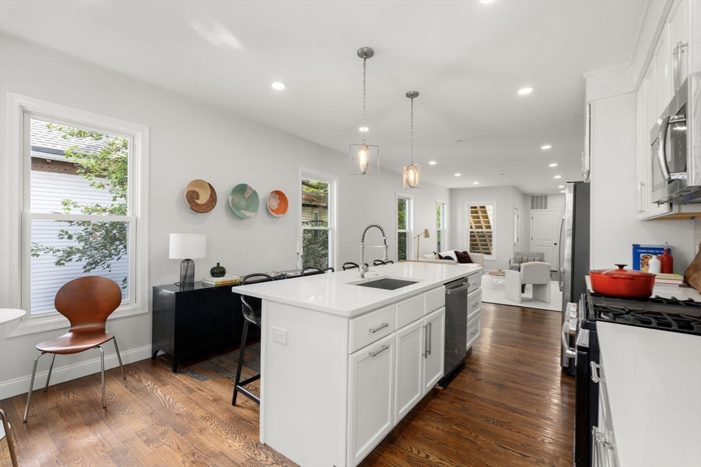 4 Wyoming Street, Unit 2 Boston, MA 02121 - Photo 9 of 23 a open kitchen with stainless steel appliances kitchen island granite countertop a sink dishwasher and white cabinets with wooden floor
