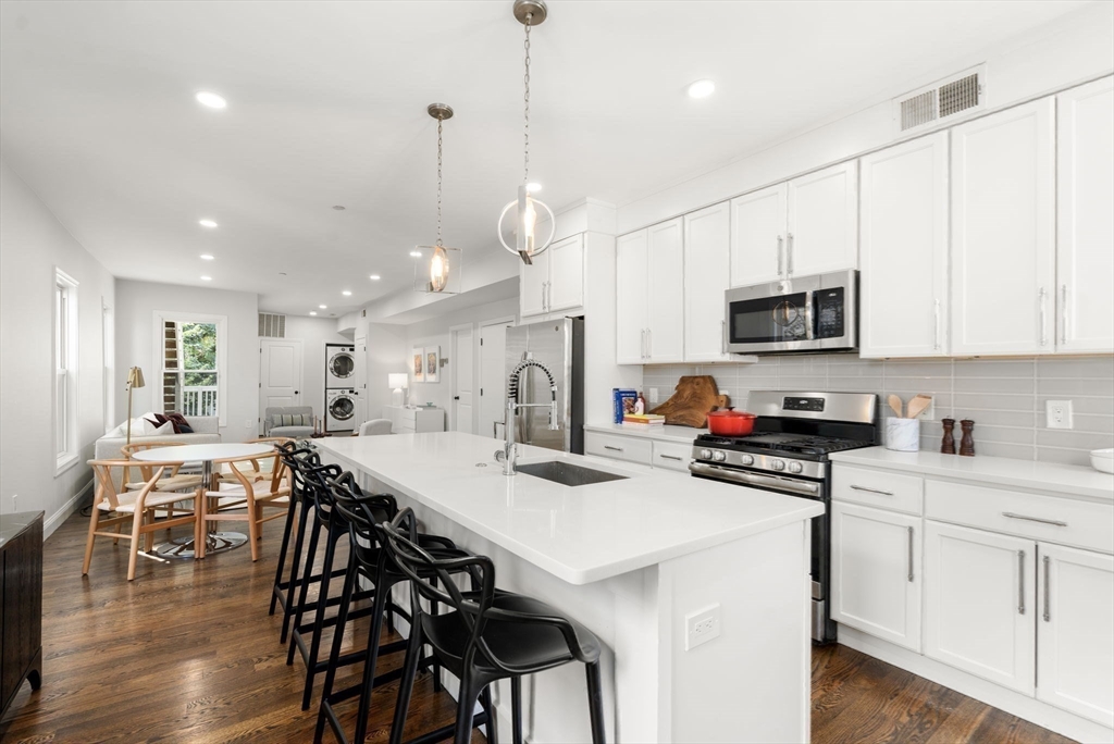 4 Wyoming Street, Unit 2 Boston, MA 02121 - Photo 10 of 23 a kitchen with stainless steel appliances kitchen island granite countertop a stove a sink a dining table and chairs