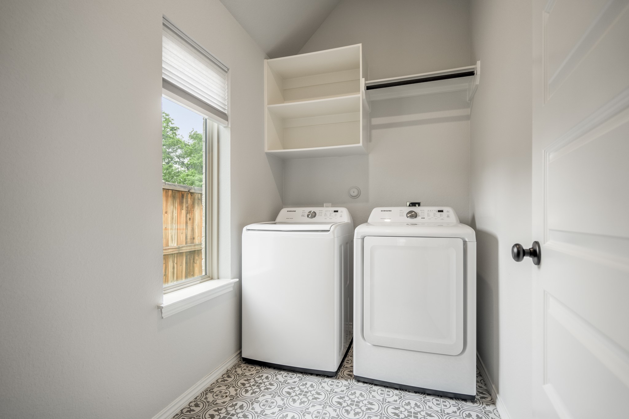 334 Topper Pines Drive Montgomery, TX 77316 - Photo 34 of 49 Stepping into the laundry room, the designer accent tile immediately gives the space more personality than expected. A large window brings in natural light, and the included washer and dryer sit below cabinet storage with a hanging rod nearby.
