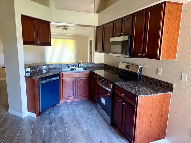 a kitchen with stainless steel appliances granite countertop wooden cabinets stove top oven and sink