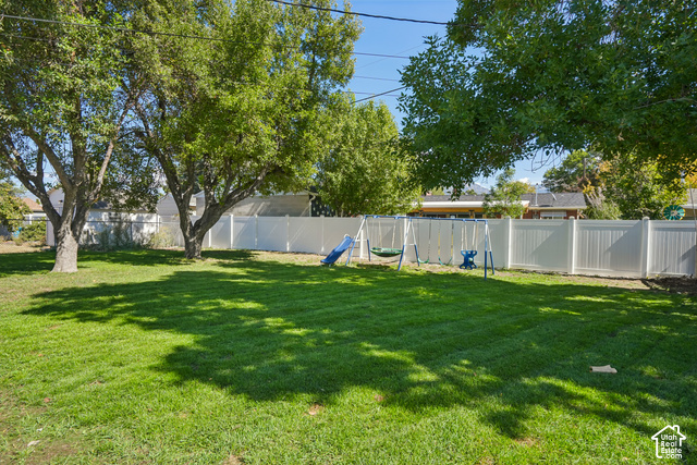 7391 Ramanee Drive Midvale, UT 84047 - Photo 35 of 45 Expansive backyard featuring a manicured lawn, mature trees, and a white panel fence